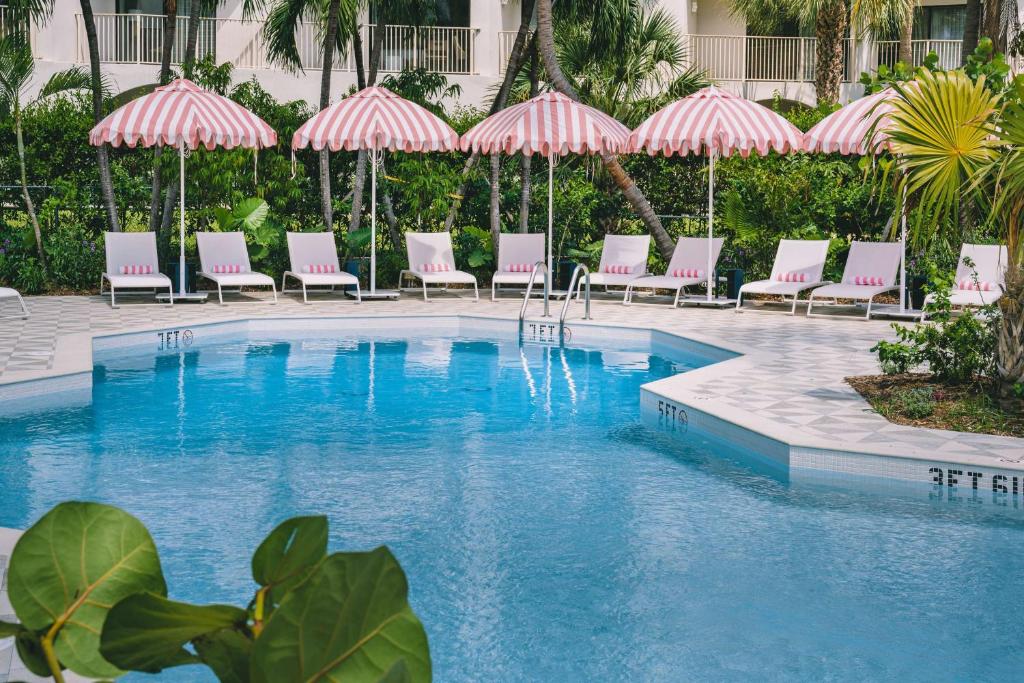 a swimming pool with chairs and umbrellas at Hampton by Hilton Grand Cayman Seven Mile Beach in George Town