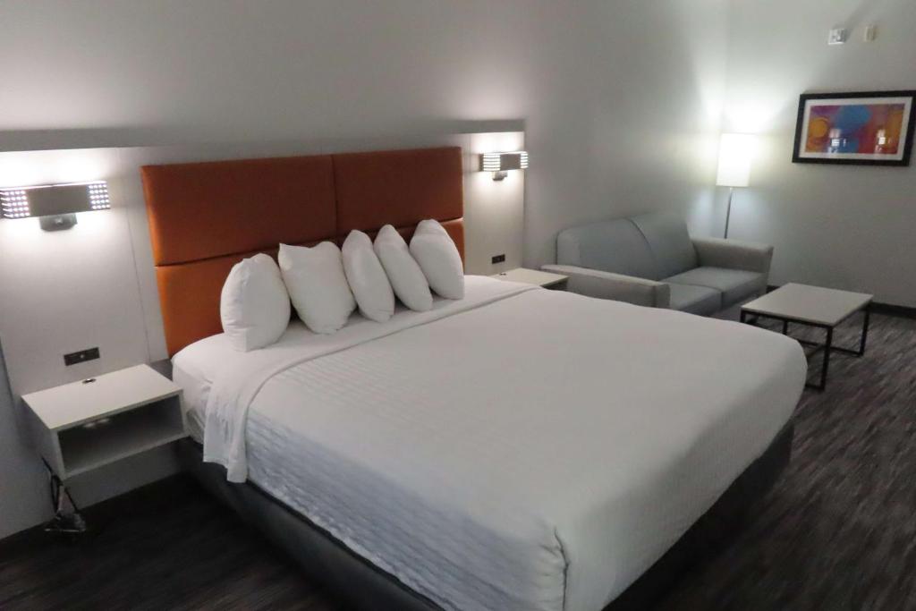 a hotel room with a large white bed and a chair at Best Western Heritage Inn & Suites in Broussard