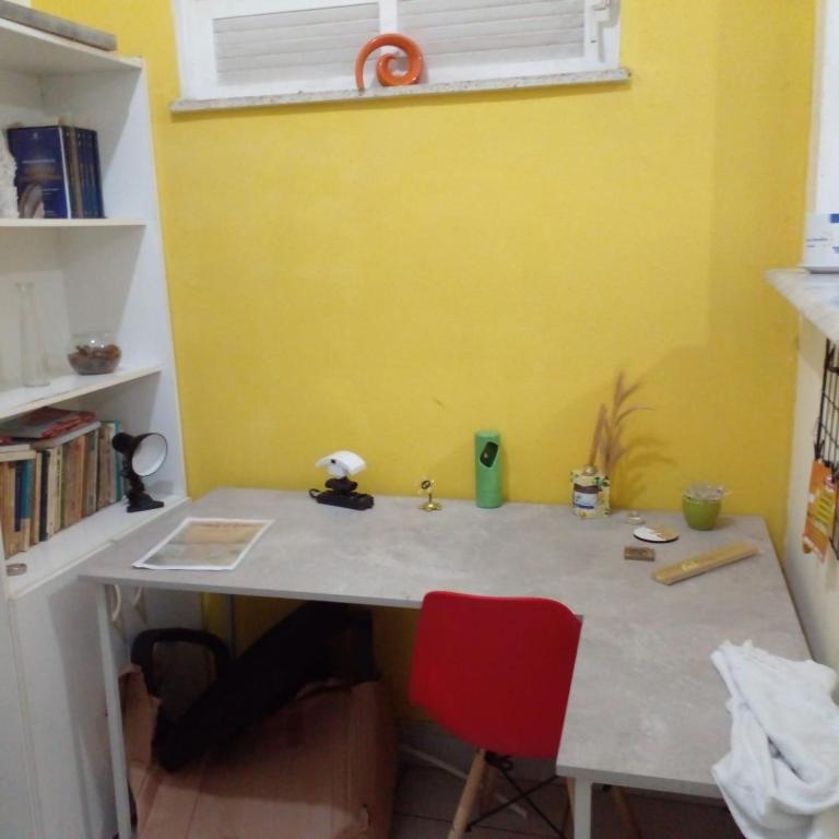 einen Schreibtisch mit einem roten Stuhl neben einer gelben Wand in der Unterkunft Copacabana aconchegante e dividido em quarto e sala in Rio de Janeiro
