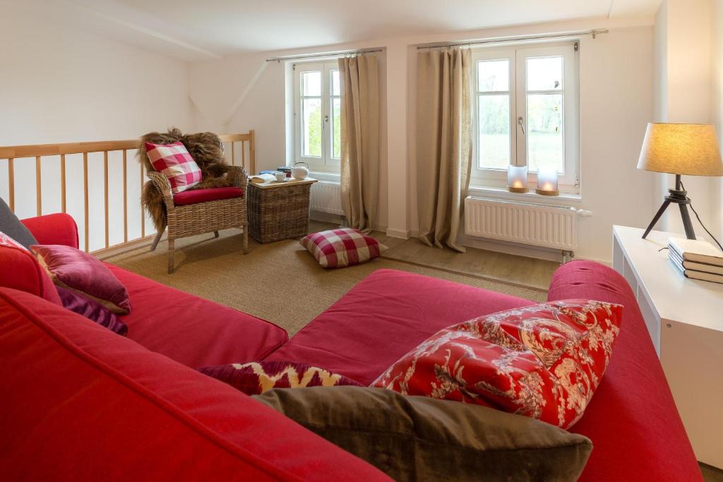 Una sala de estar con un sofá rojo y una silla. en Herthaquelle Wohnung 3 "Die Rose", en Garz
