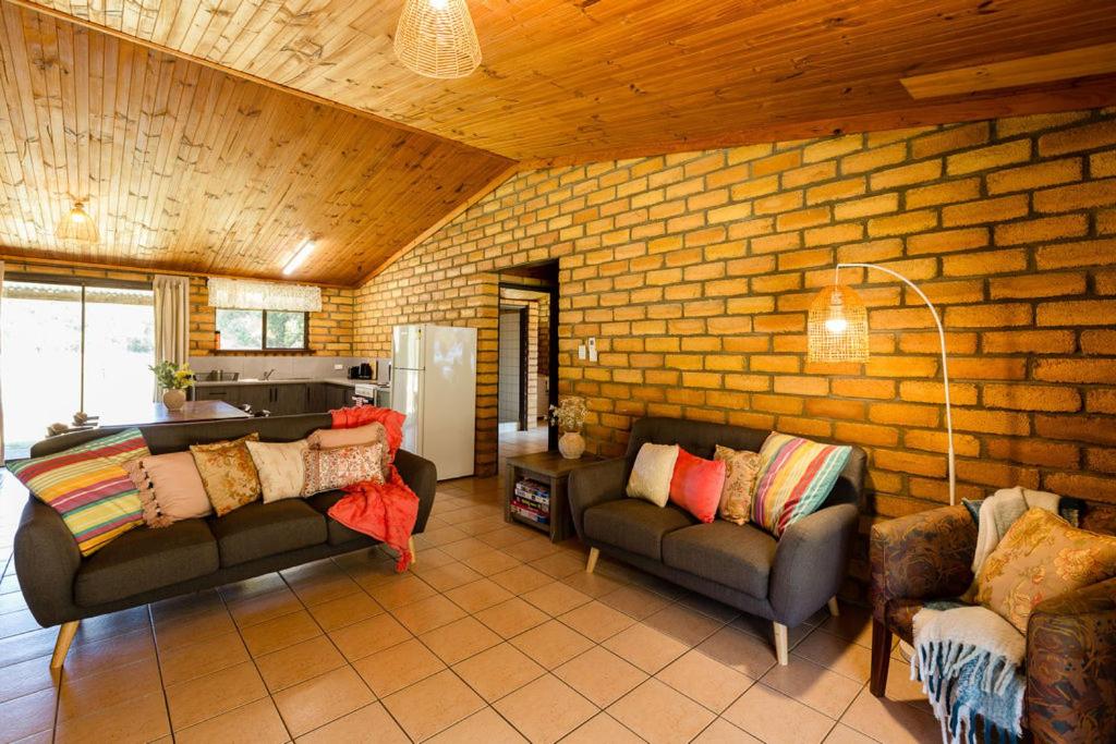 a living room with two couches and a brick wall at Turner Brook in Augusta