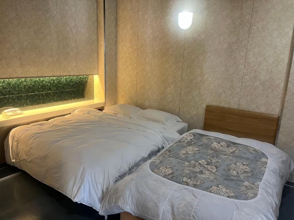 a small bedroom with two beds and a window at Higashi Kumamoto Business Center in Ozu