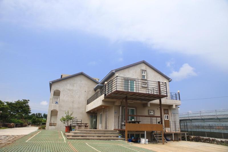 a large building with a balcony on top of it at Sanbangsan Hot Spring Pension in Seogwipo