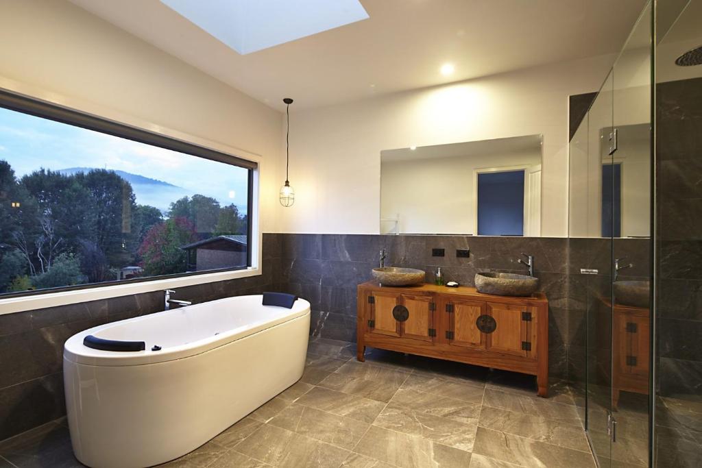 ein Bad mit einer Badewanne, einem Waschbecken und einem Fenster in der Unterkunft Blue Haven In Bright Victoria in Bright