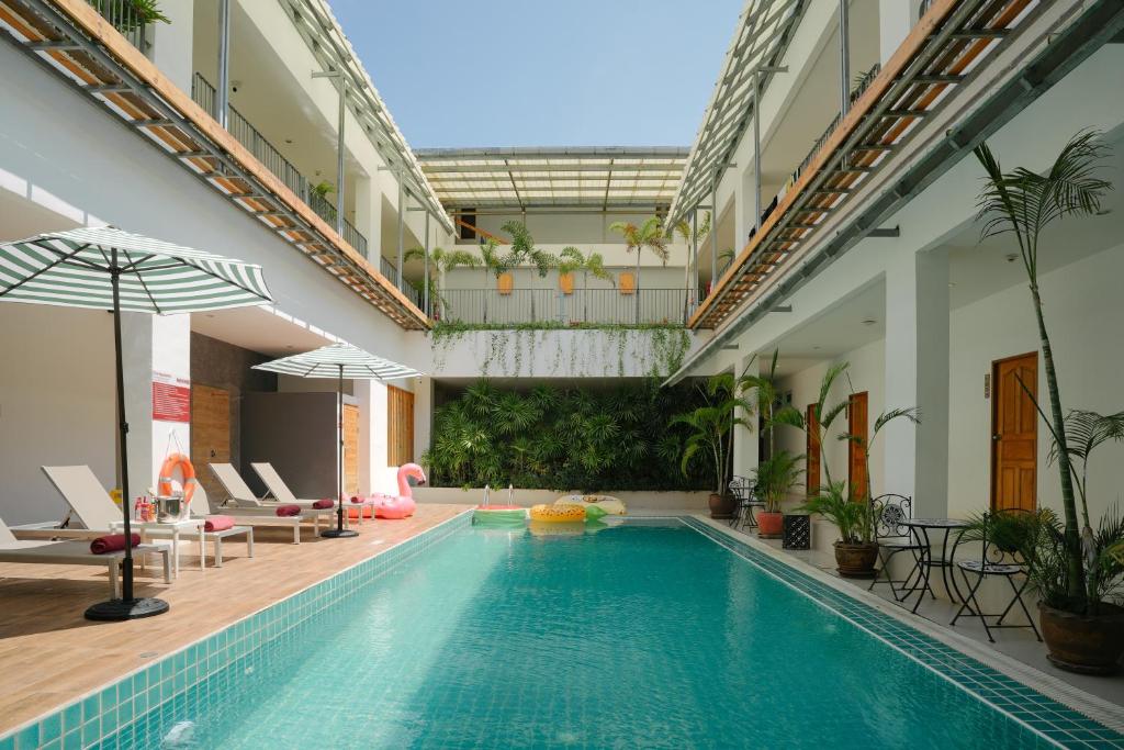 a swimming pool in a building with chairs and umbrellas at Nonnee Hotel Kata Beach Phuket in Kata Beach