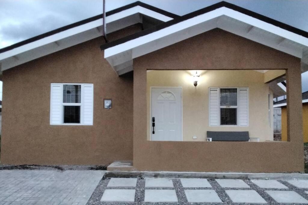 a small house with a white door on it at Home Away From Home in Old Harbour