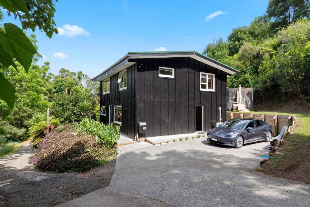 een zwart huis met een auto ervoor geparkeerd bij Raglan Country Lodge in Raglan