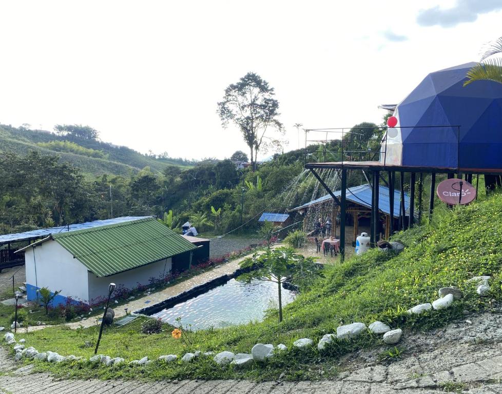 a building on a hill next to a pool of water at Hotel Glamping Horse in Dosquebradas