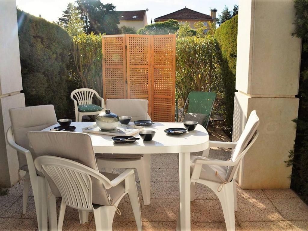 une table blanche et des chaises sur une terrasse dans l'établissement Studio cabine climatisé avec terrasse, 2 pas de la plage, 4 couchages, ménage inclus - Cavalière - FR-1-251-554, au Lavandou