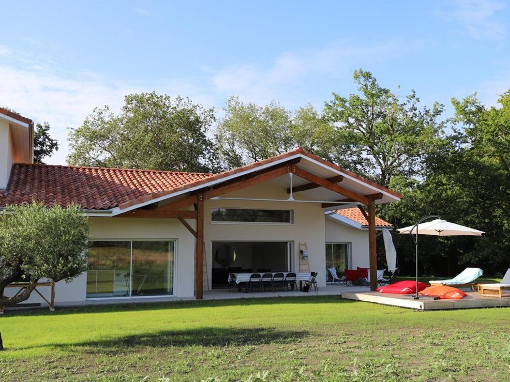 une maison avec une terrasse et un parasol dans l'établissement Villa avec piscine, 10 pers, au calme, climatisée, terrasse, grand jardin - FR-1-379-169, à Soustons