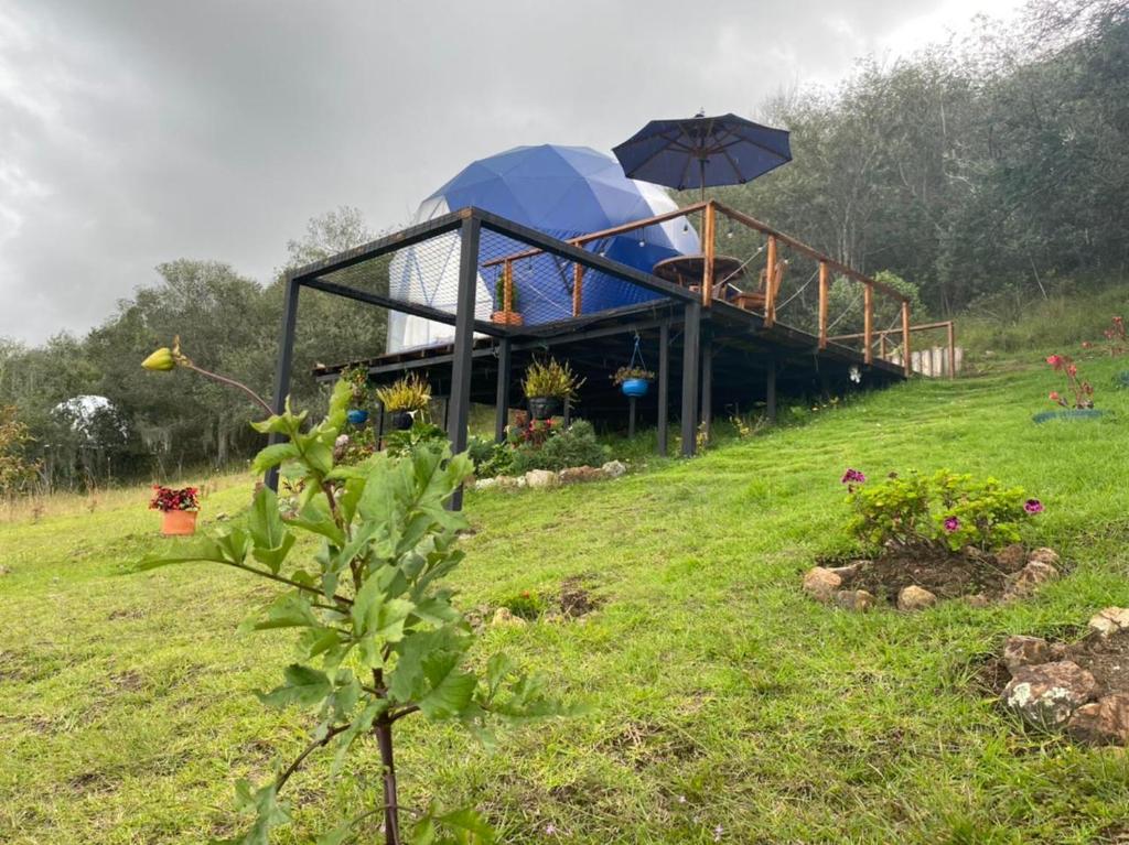 uma casa no topo de uma colina com um guarda-chuva em Glamping blue. em Guatavita
