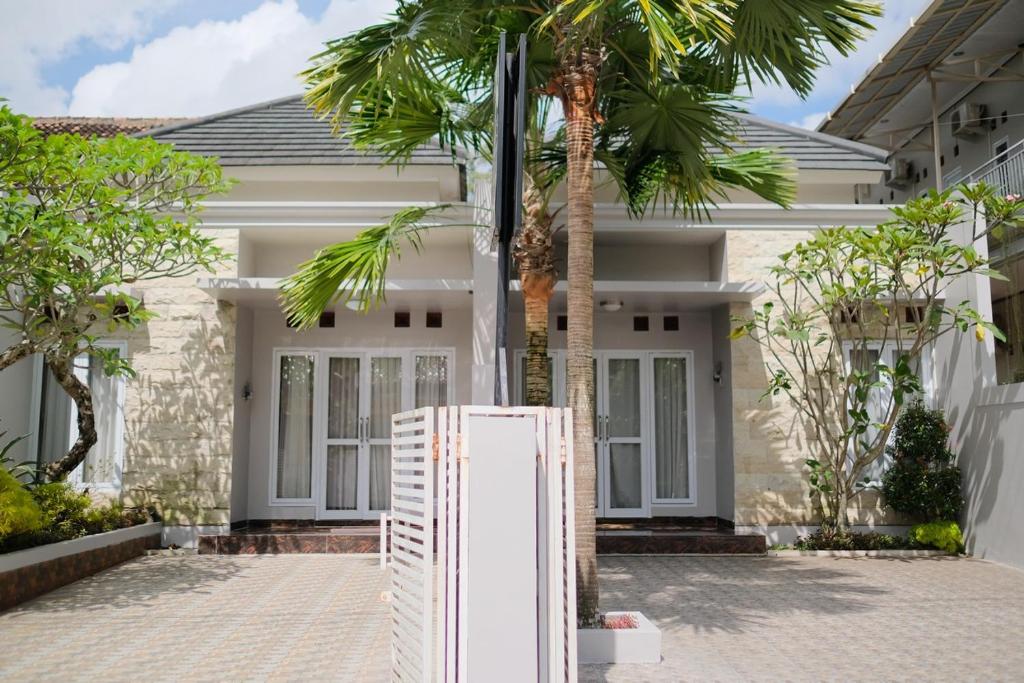 - un réfrigérateur blanc devant une maison avec des palmiers dans l'établissement Kays Homestay Jogja, à Ngemplak