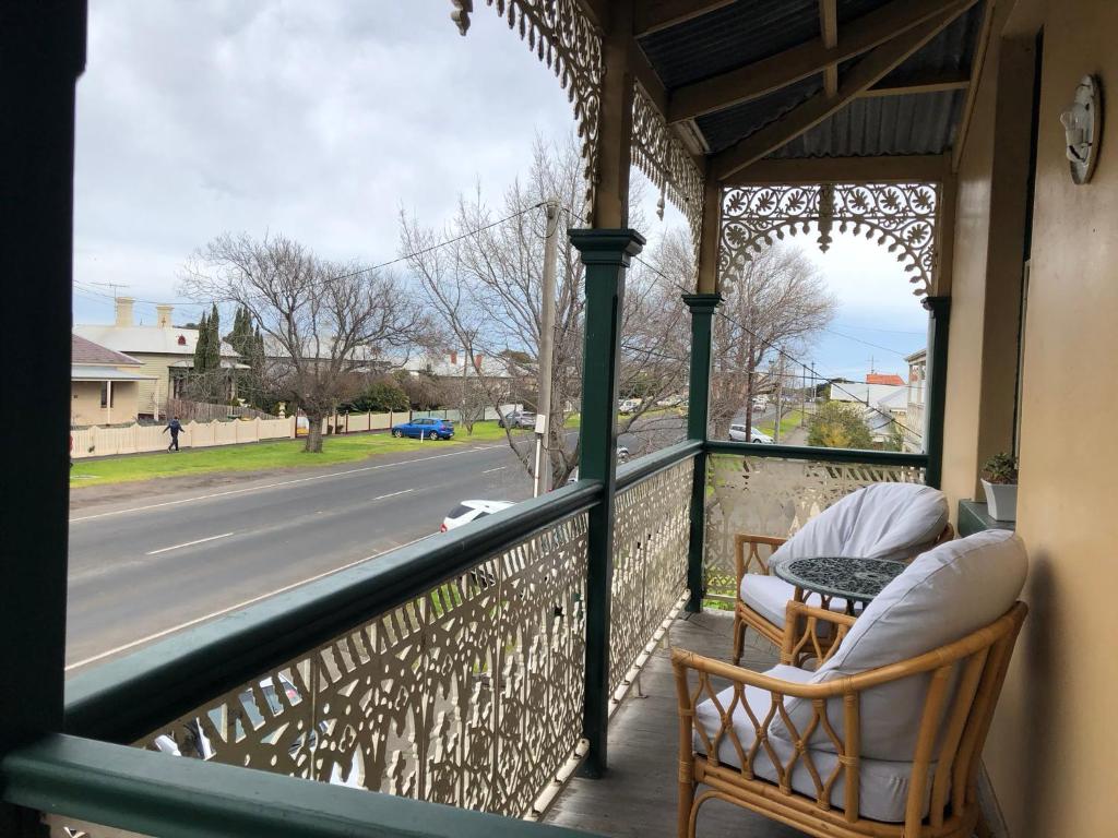 a porch with two chairs and a table and a street at Seaview House in Queenscliff
