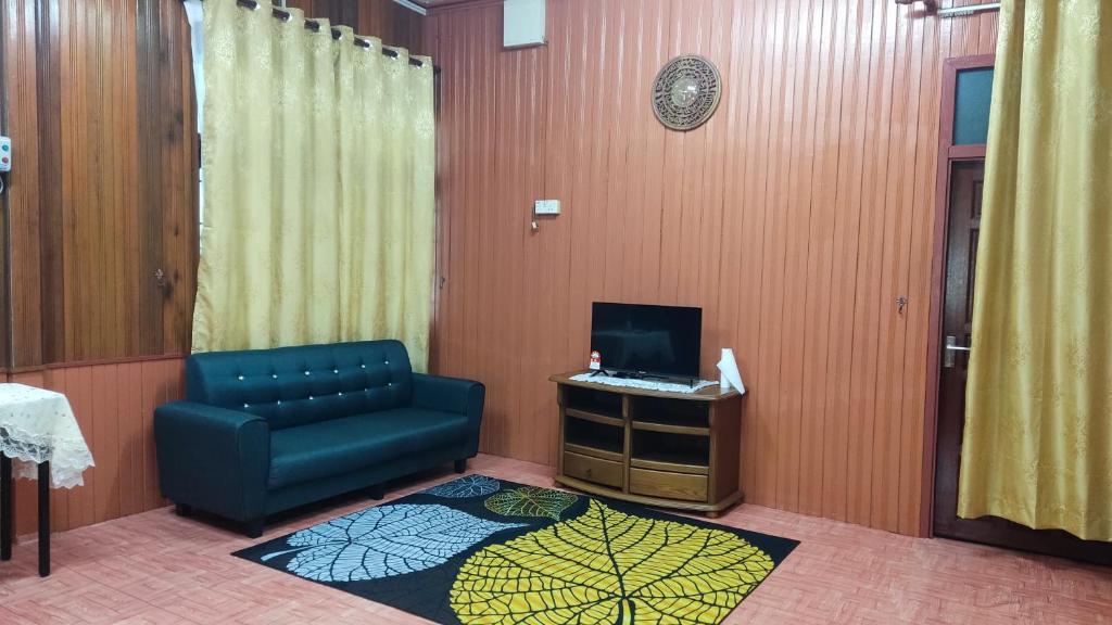 uma sala de estar com uma cadeira azul e uma televisão em Nik Legacy Homestay em Pasir Puteh