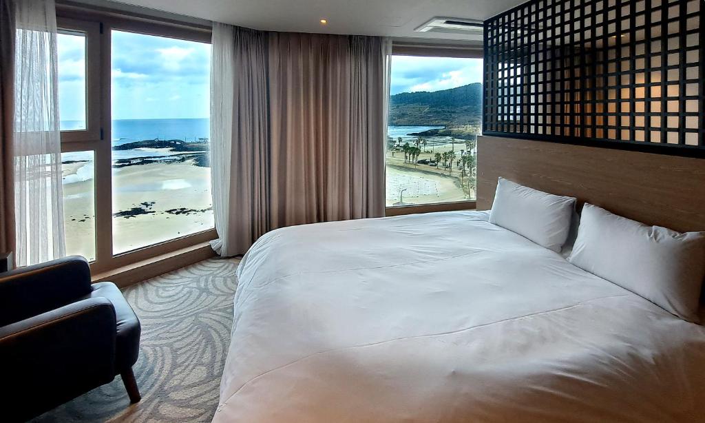 a bedroom with a large bed and a large window at Saint Beach Hotel in Jeju