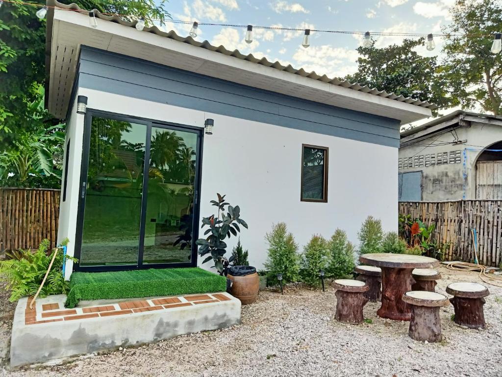 a small white house with a table and stools at Home No 3 khanom in Ban Thung O