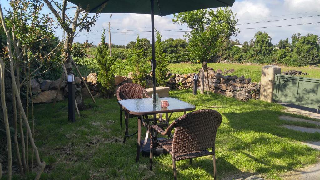 a table and chairs under an umbrella in the grass at Sopoong in Jeju