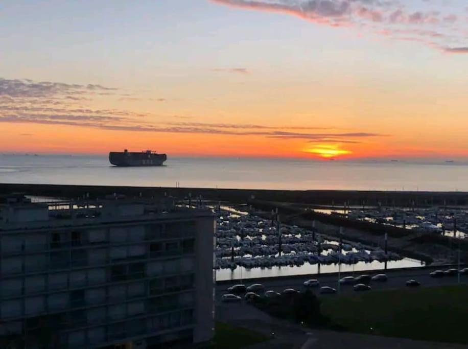 a sunset over a parking lot with a ship in the water at La Marée, Studio vu mer Le Havre in Le Havre