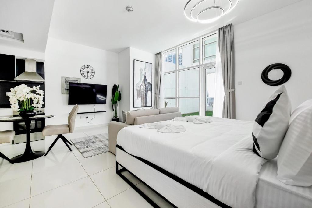 a white bedroom with a bed and a living room at Primestay - Park Central Studio - Business Bay in Dubai