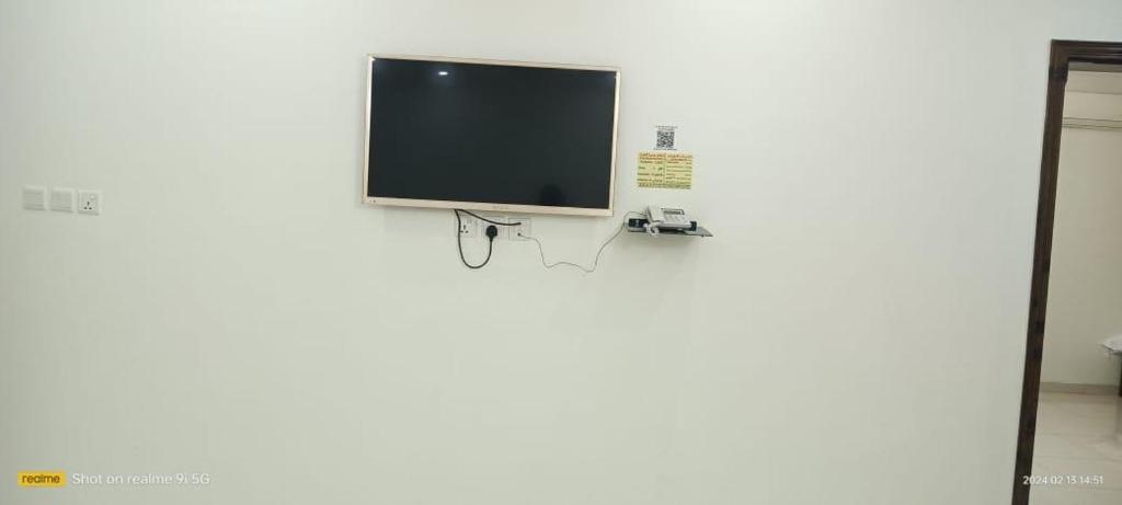 a flat screen tv hanging on a white wall at فندق رفال الغربية للشقق المخدومة in Ukaz