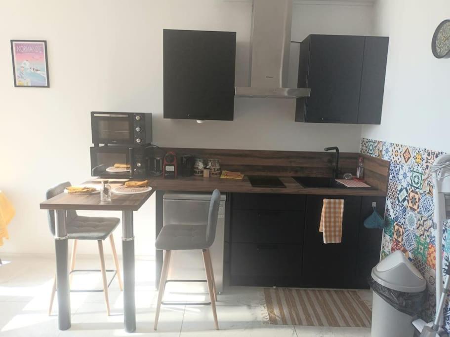 a kitchen with a table and two chairs and a counter at La Marée, Studio vu mer Le Havre in Le Havre