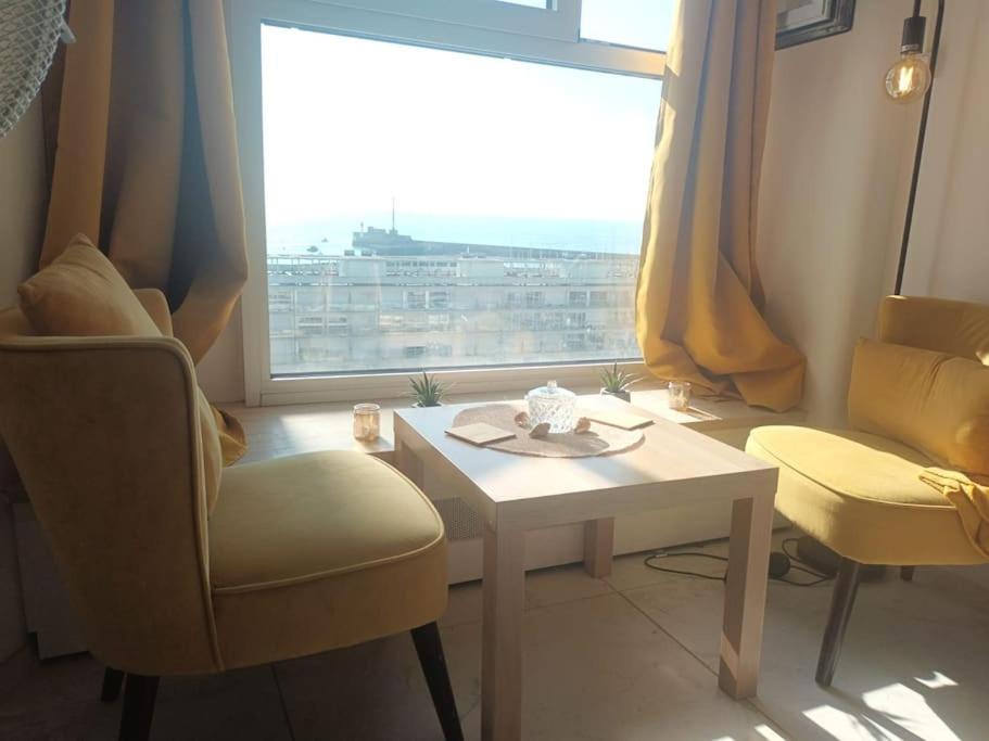 a living room with a table and a large window at La Marée, Studio vu mer Le Havre in Le Havre
