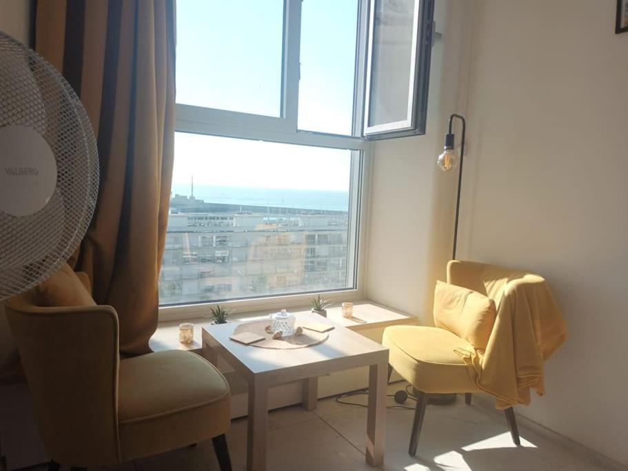 a living room with a table and a window at La Marée, Studio vu mer Le Havre in Le Havre