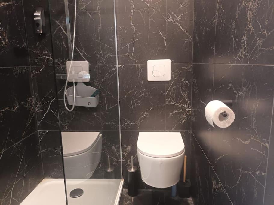 a black tiled bathroom with a toilet and a sink at La Marée, Studio vu mer Le Havre in Le Havre