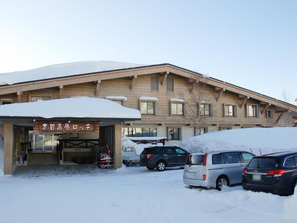 un bâtiment enneigé avec des voitures garées dans un parking dans l'établissement Shiga Kogen Lodge, à Yamanouchi