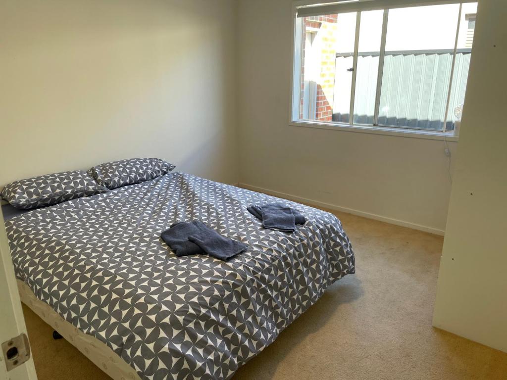 a bedroom with a bed with two towels on it at Comfy Newly Furnished Queen bedroom in Point Cook