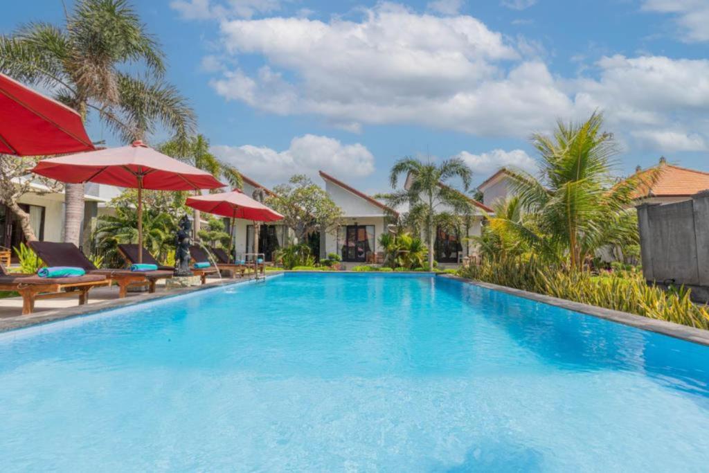 una grande piscina con sedie e ombrelloni di Favorit Exclusive Villa & Bungalow a Nusa Penida