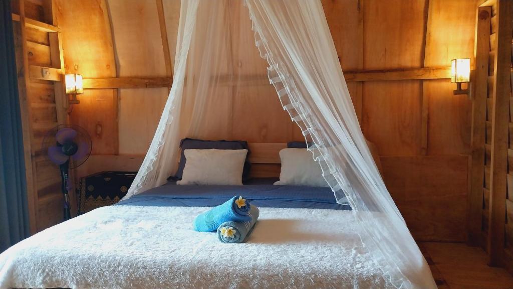 un osito de peluche sentado en una cama con dosel en Raturinjani homestay en Selong