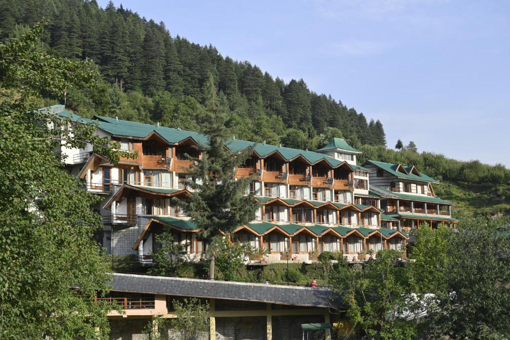 a large hotel on the side of a mountain at Manuallaya The Resort & Spa in Manāli
