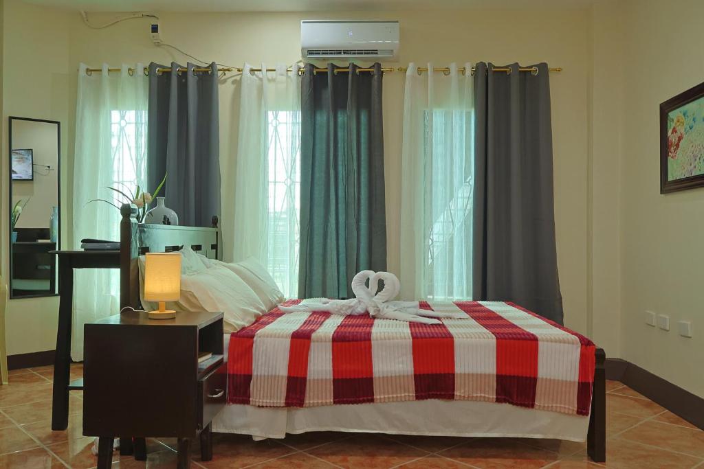 a bedroom with a bed with a red and white blanket at Point Vista Transient Accomodation in Daet