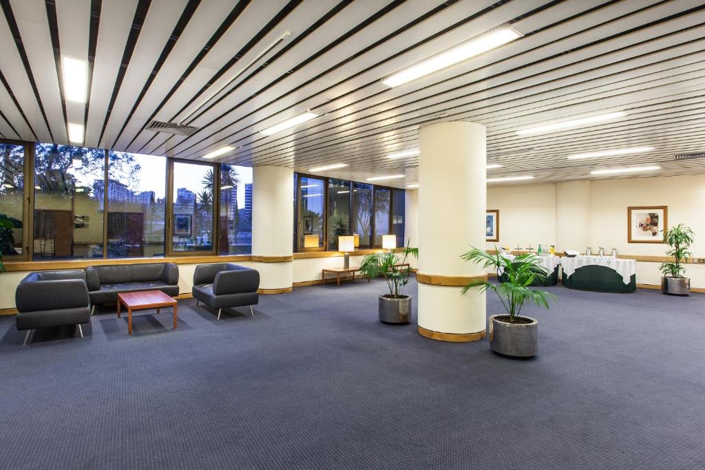 A broad carpeted lobby stretches around columns, windows, and scattered seating.