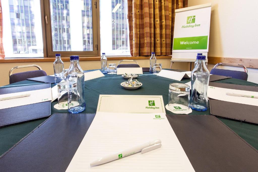 A small meeting room set with a central table, stationery, and bottled water.