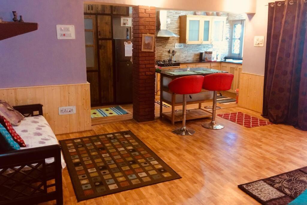 a kitchen with two red stools and a counter at Well-equipped modern flat with 24/7 security in Srinagar