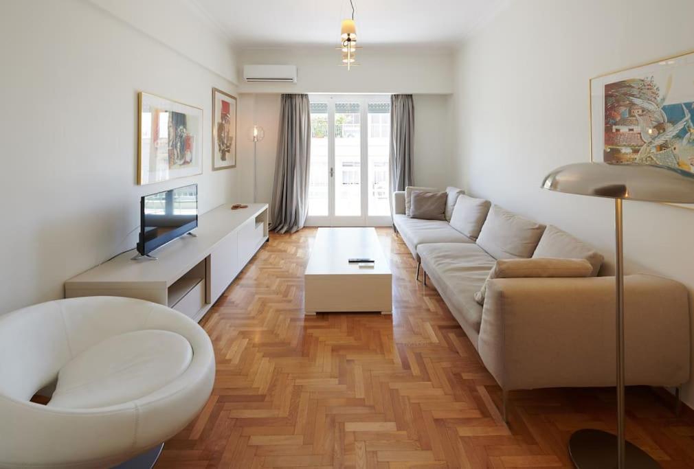 sala de estar con sofá blanco y TV en Apartment in the heart of the city en Atenas