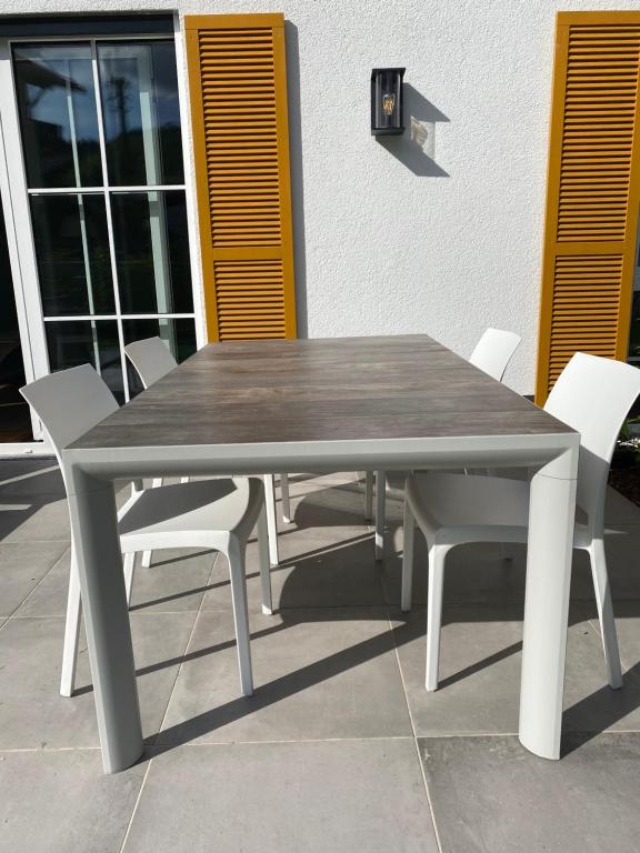 uma mesa de madeira e cadeiras brancas num pátio em Das Bad Wiessee 22 em Bad Wiessee