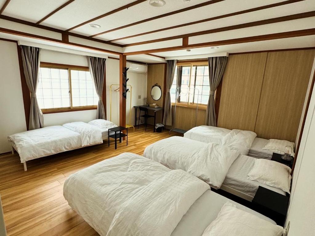 een kamer met 3 bedden en een tafel en ramen bij HAKUBA76 in Hakuba