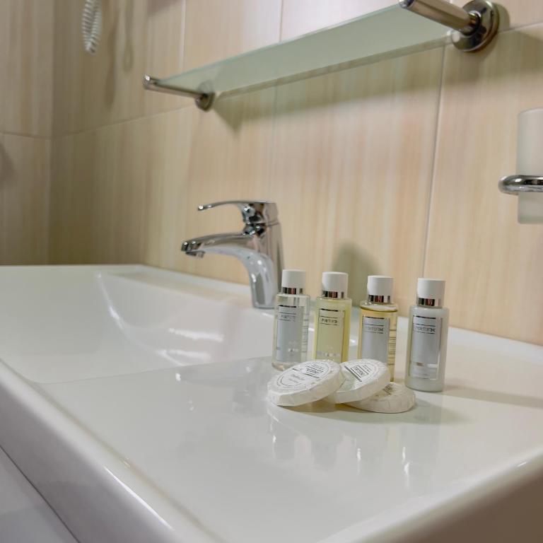 a bathroom sink with three bottles ofodorizers on it at Hotel Opera Jaz in Budva