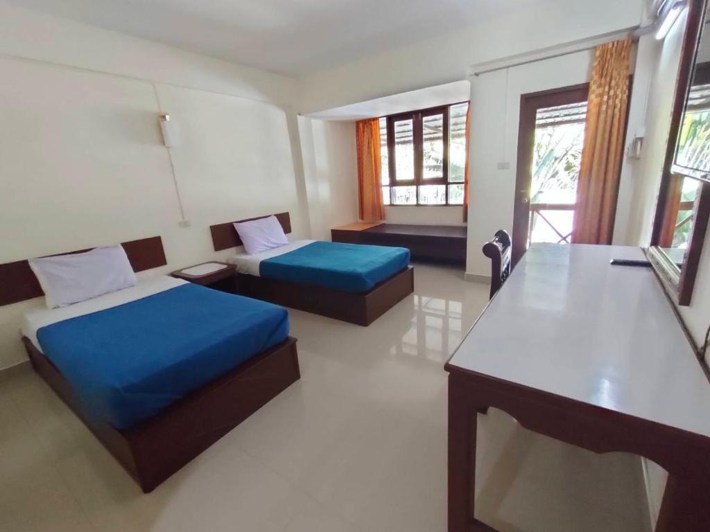 een kamer met 2 bedden, een tafel en ramen bij โรงแรมสบายโฮเต็ล 