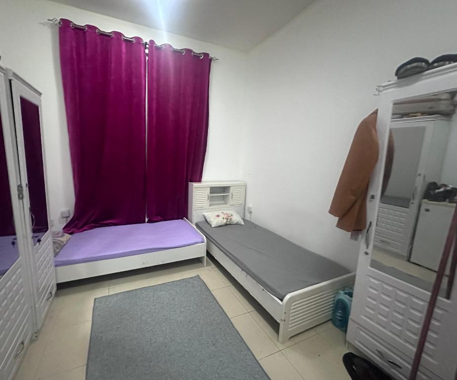 a small room with a purple curtain and a bed at Ladies Hostel in Ajman سكن بنات بعجمان in Ajman 