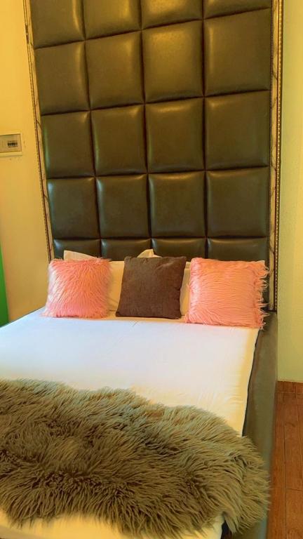 a bed with a leather headboard and three pillows at Allooo Docteur in Douala