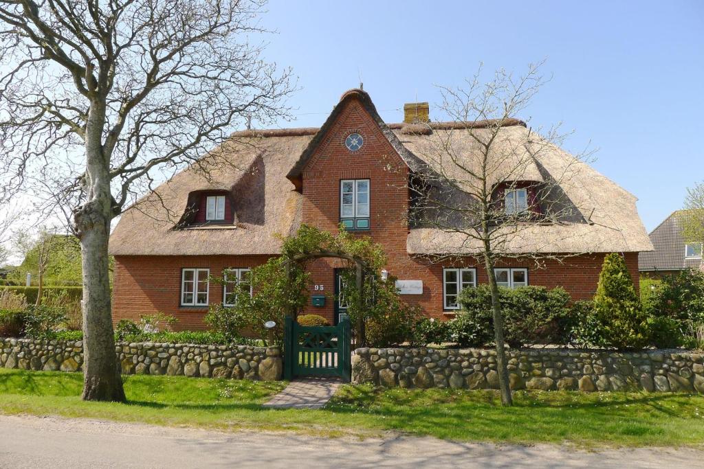 uma grande casa de tijolos vermelhos com uma cerca de pedra em Annes Cottage 2 em Oevenum