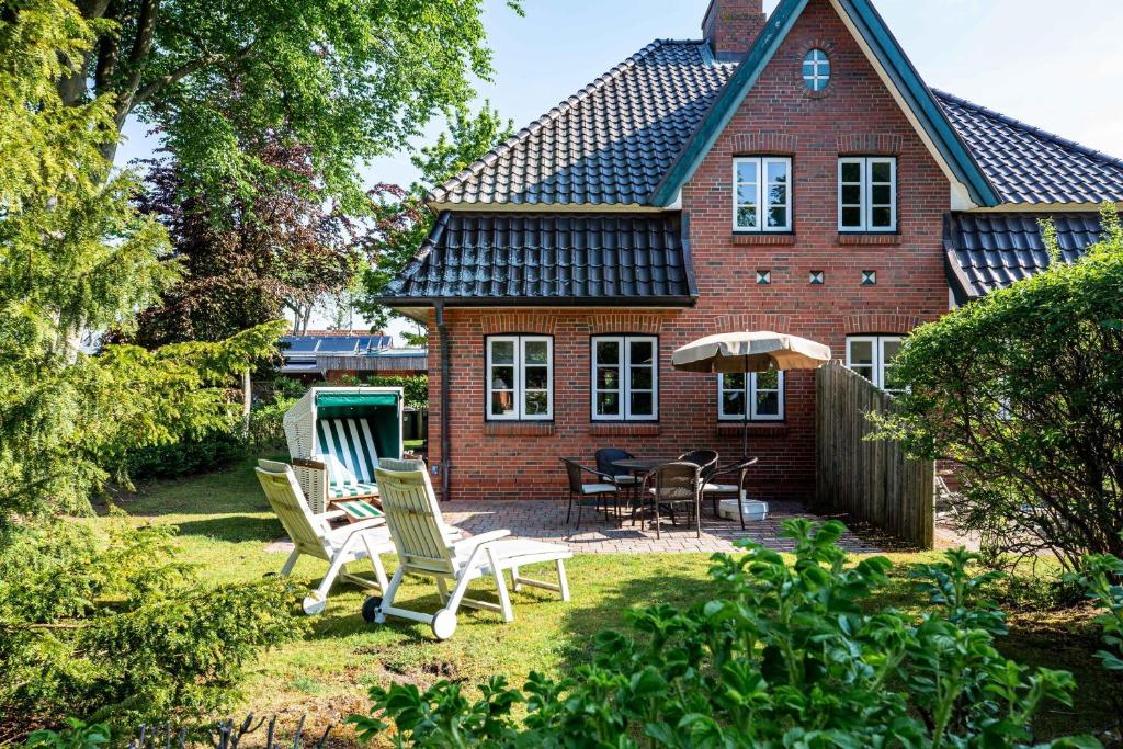een stenen huis met stoelen en een parasol in de tuin bij Annes Strandhaus in Wyk auf Föhr