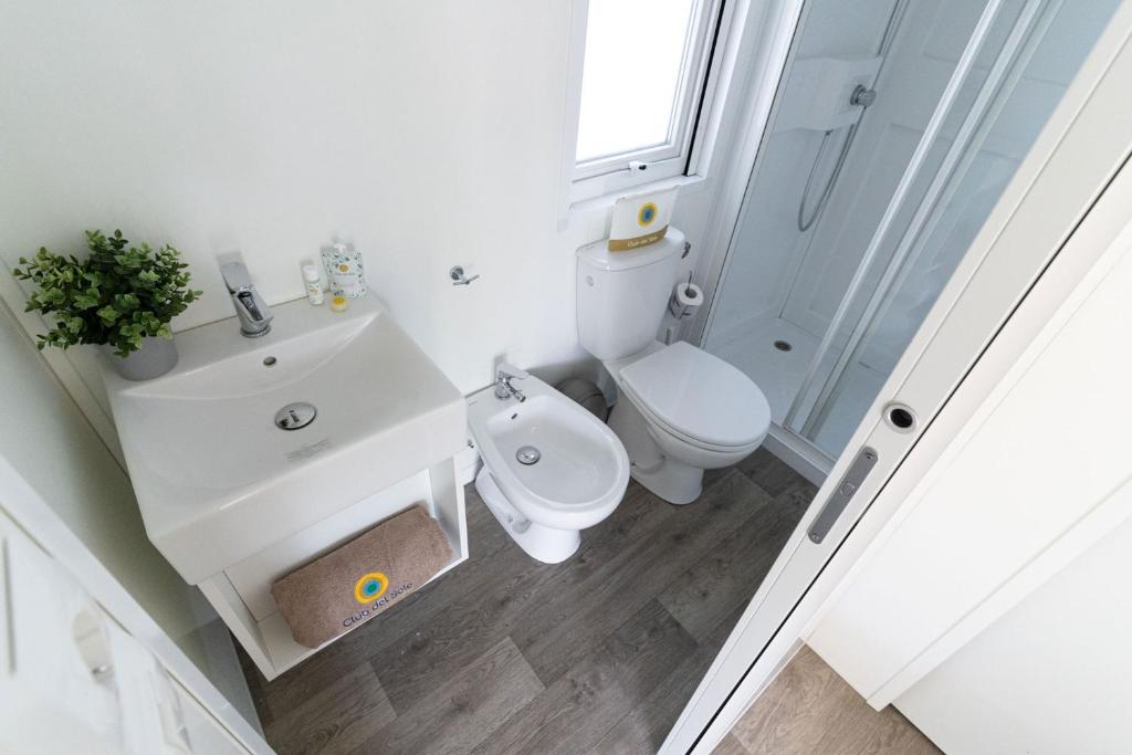 a white bathroom with a toilet and a sink at Club del Sole Rimini Family Resort in Rimini