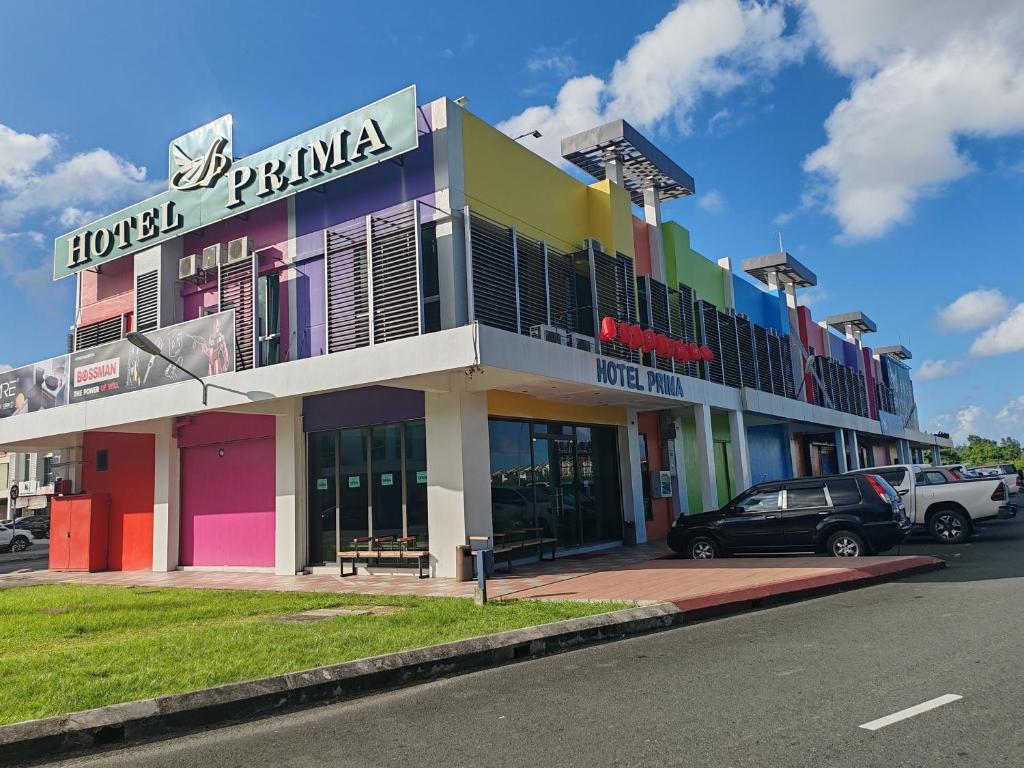 un edificio colorido con coches estacionados frente a él en Hotel Prima en Sandakan