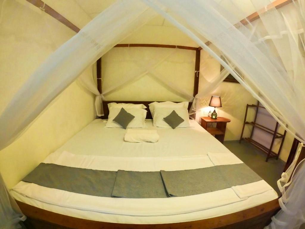 a bedroom with a white bed with a canopy at Ostello Surf Resort in Ahangama