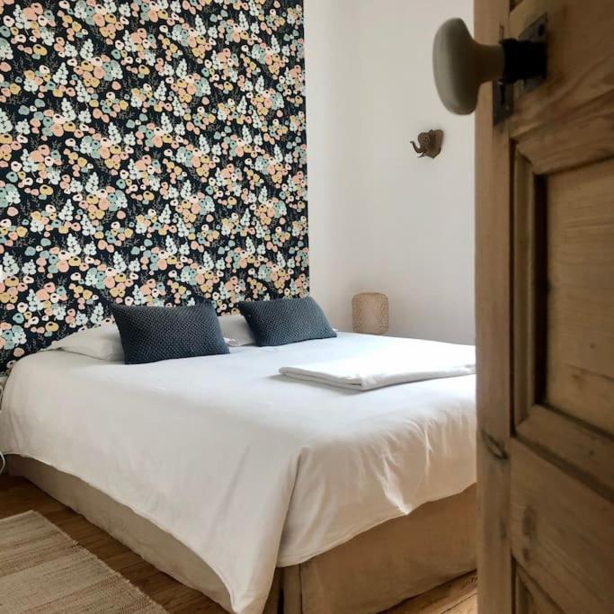 - un lit dans une chambre avec un mur fleuri dans l'établissement Maison de vacances, proche de la Baie de Somme, à Sailly-Flibeaucourt